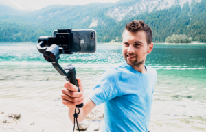 Mann am See mit einem Gimbal, er macht Selfies mit seinem Smartphone, Eibsee in Bayern