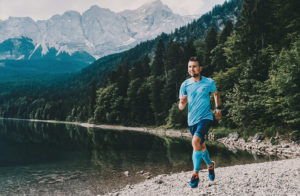 Mann läuft am Eibsee, Berge und Wasser im Hintergrund