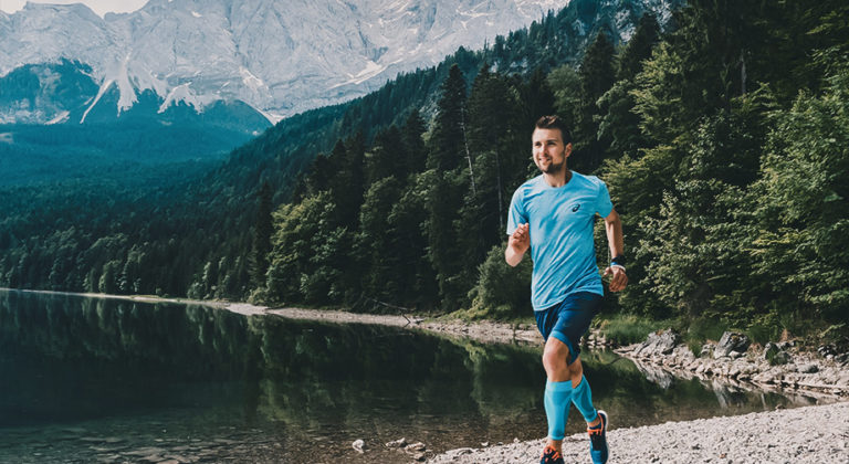 Mann läuft am Eibsee, Berge und Wasser im Hintergrund